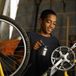 DIY bike service: How to service a bike at home. A boy oiling his bike chain.