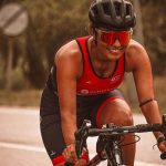 Our guide to sunglasses for cycling and our top picks. Woman smiling cycling and wearing cycling sunglasses.